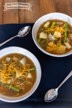  Tazón con sopa de espárragos y papas cubierta con queso cheddar.