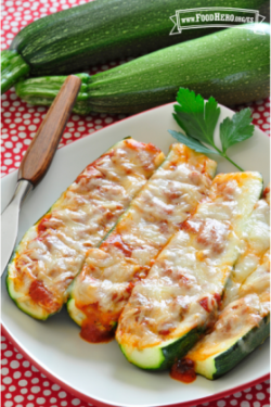 Plato con mitades de calabacita al horno rellenas con salsa roja y queso derretido.