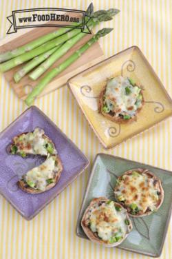 English muffins topped with chopped asparagus, mushrooms and broiled cheese are shown on plates.