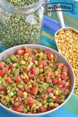 Bowl with a vibrant mix of split peas, tomato and parsley.