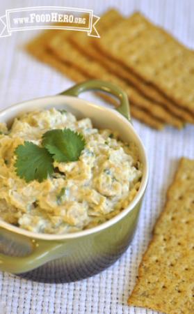 Garbanzo bean dip garnished with cilantro and served with crackers. 