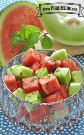 Glass bowl of watermelon and honeydew cubes with mint.