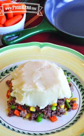 Plate of a ground beef and vegetable mix with a layer of mashed potato on top.