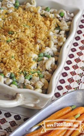 Casserole dish of creamy noodles with peas and turkey topped with crushed corn flakes.